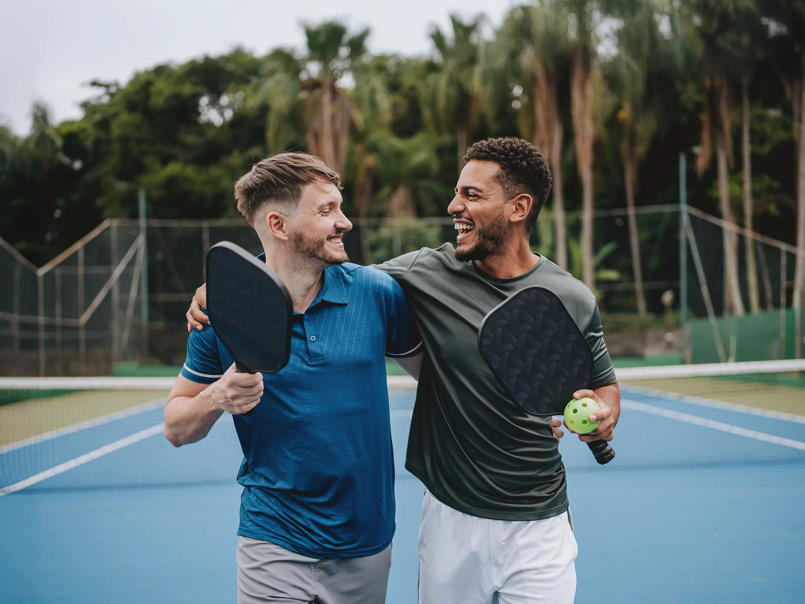Twee mannen staan lachend op een pickleballbaan